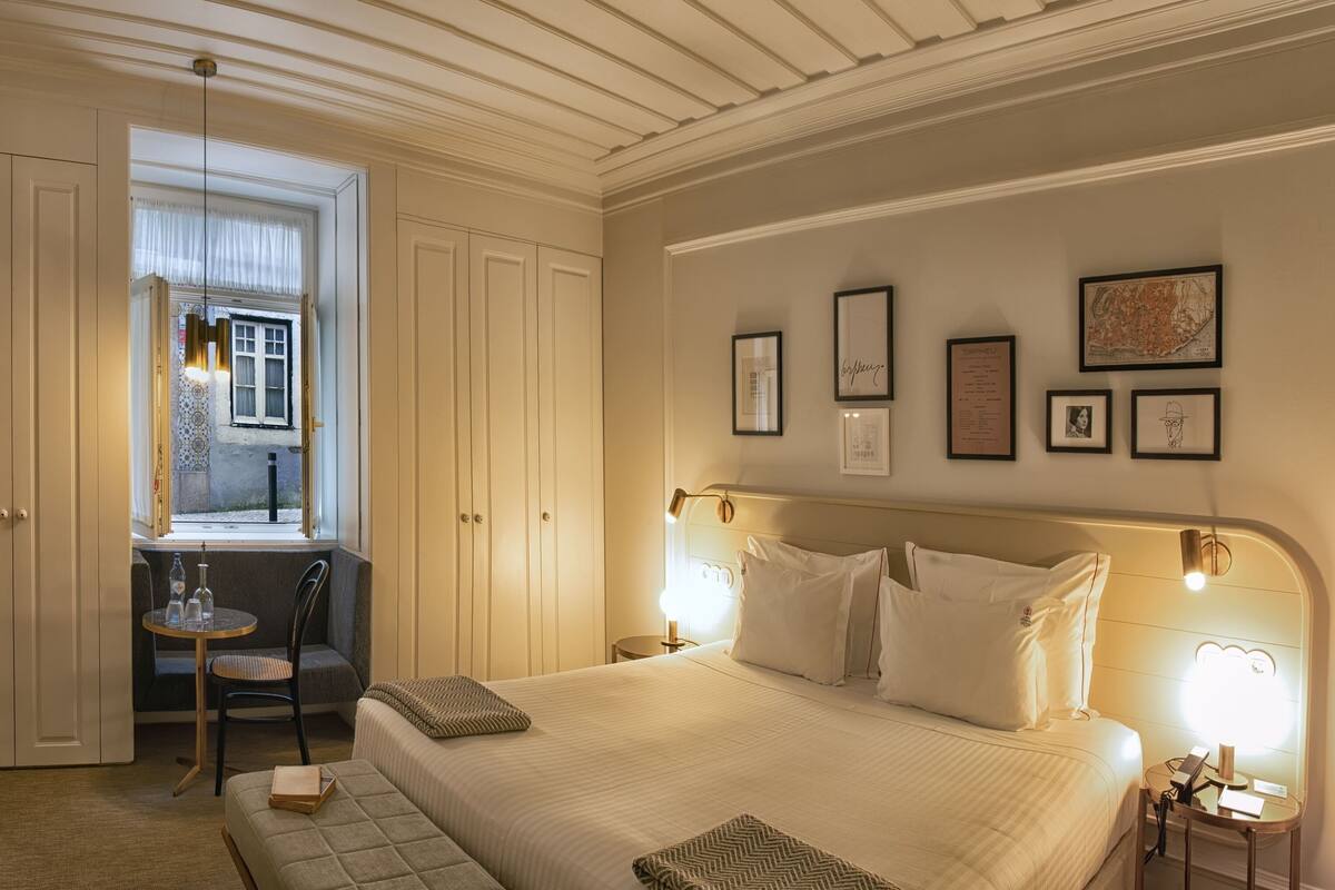 Une chambre d’hôtel dotée d’un grand lit, d’un coin salon avec une table et des chaises, et d’une fenêtre donnant sur la rue.