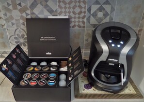 A coffee machine and a box of coffee pods with a label reading "The Extraordinary Espresso Experience". - Al 325 rooms ai Fori (Rome)