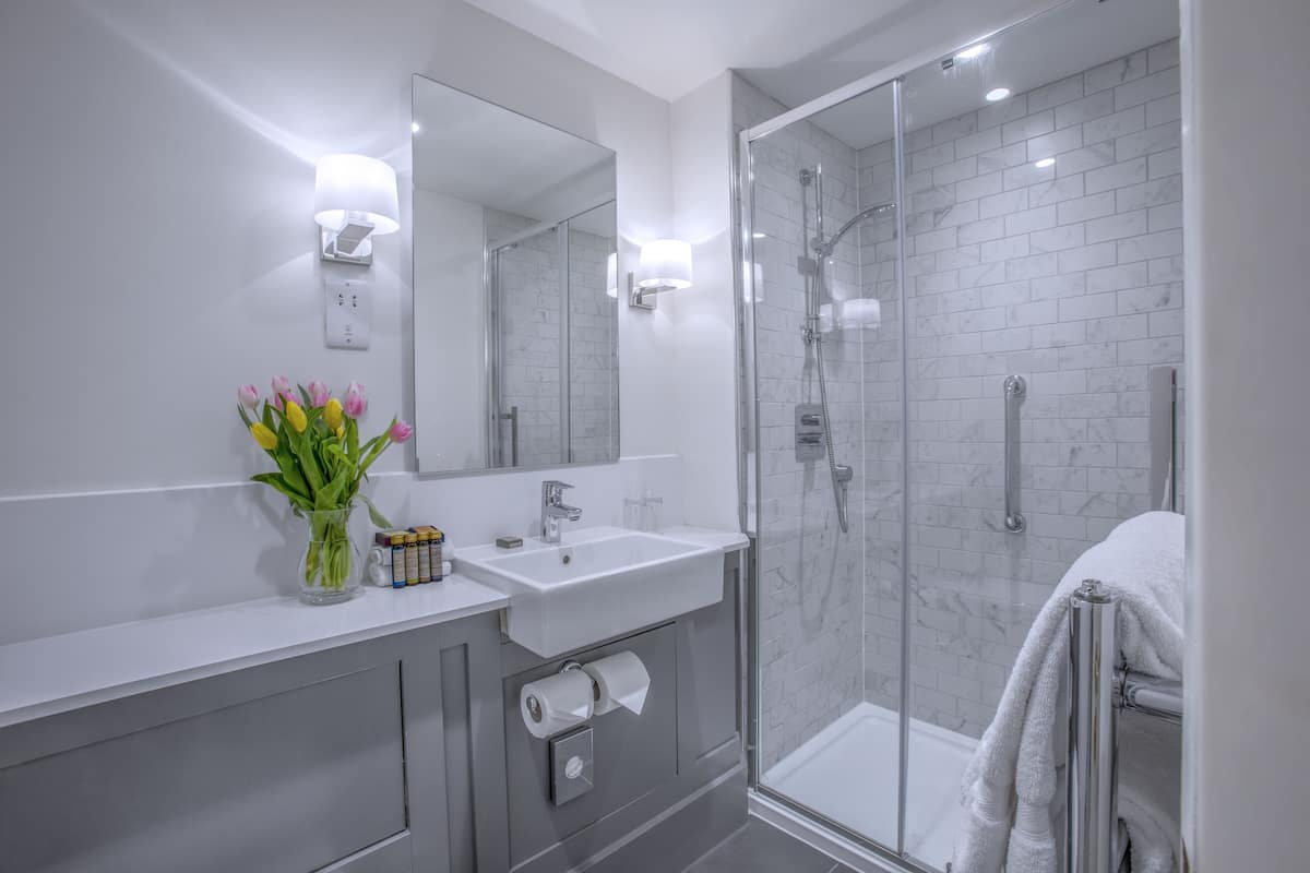 A modern bathroom with a glass-enclosed shower, a white sink, and a mirror above it.