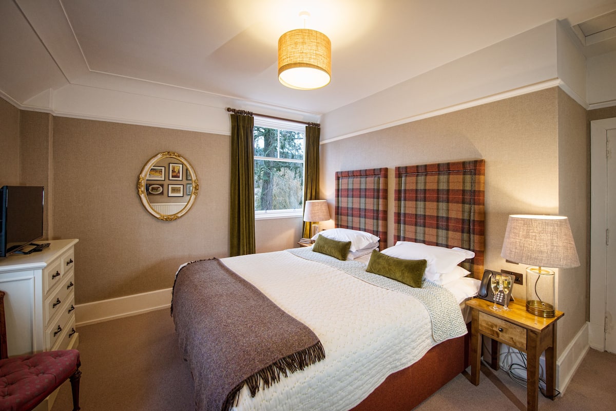 A neatly arranged bedroom with a bed, bedside table, lamp, and a dresser.