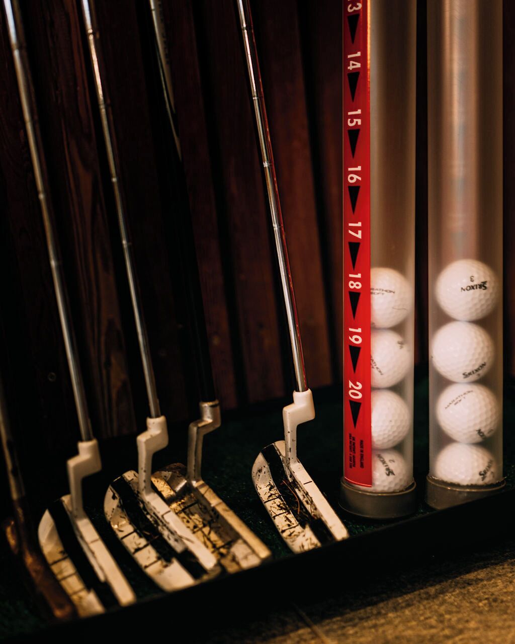 A golf bag rack with multiple bags and a container of golf balls.