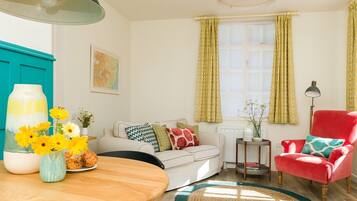 A cozy living room with a wooden dining table, a red armchair, a white sofa, and a small side table.