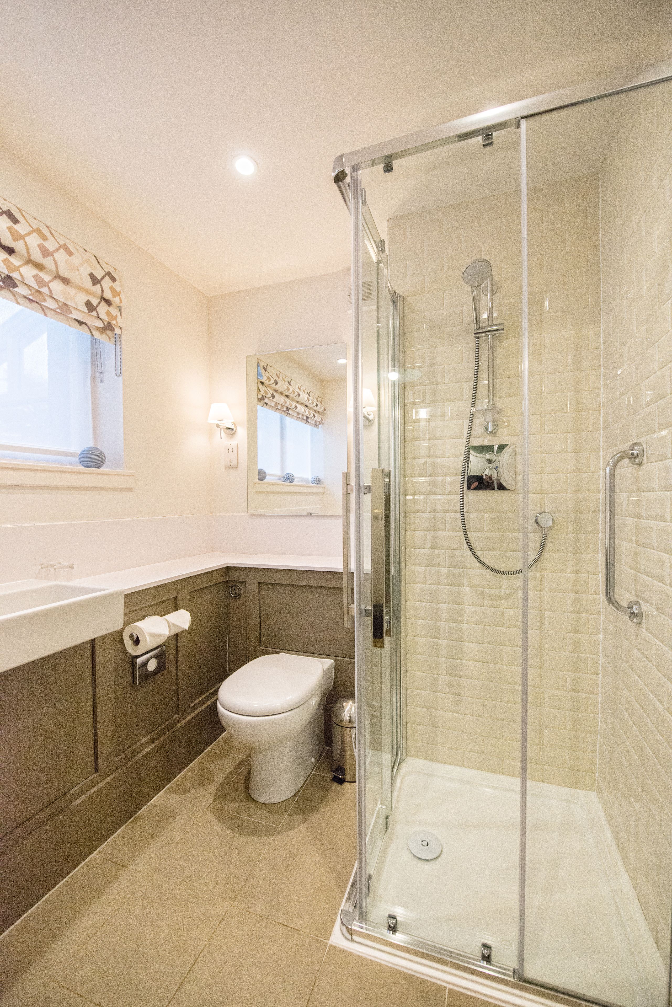 Une salle de bain moderne dotée d’une douche à parois de verre, de toilettes et d’un lavabo.
