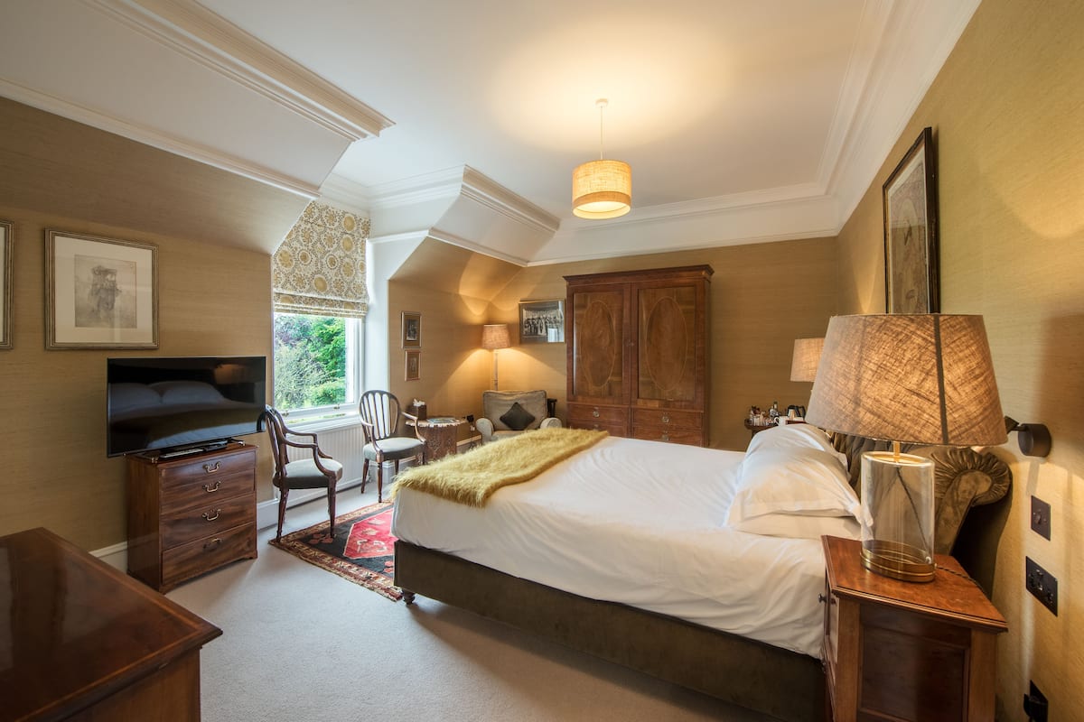 A bedroom with a bed, a television, a desk, and a chair.