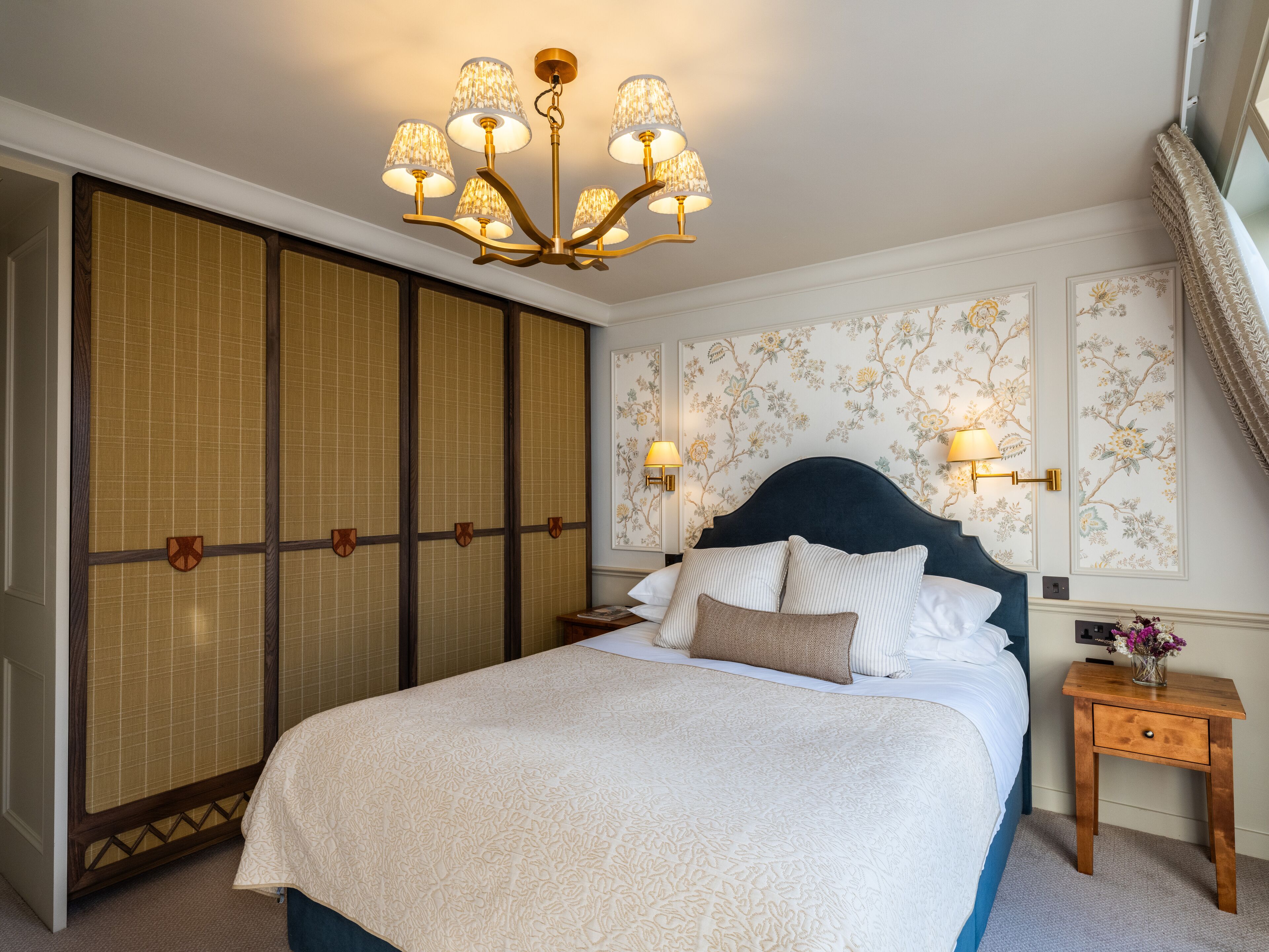 Un dormitorio ordenado con una cama grande, una puerta corredera tradicional y un candelabro decorativo.
