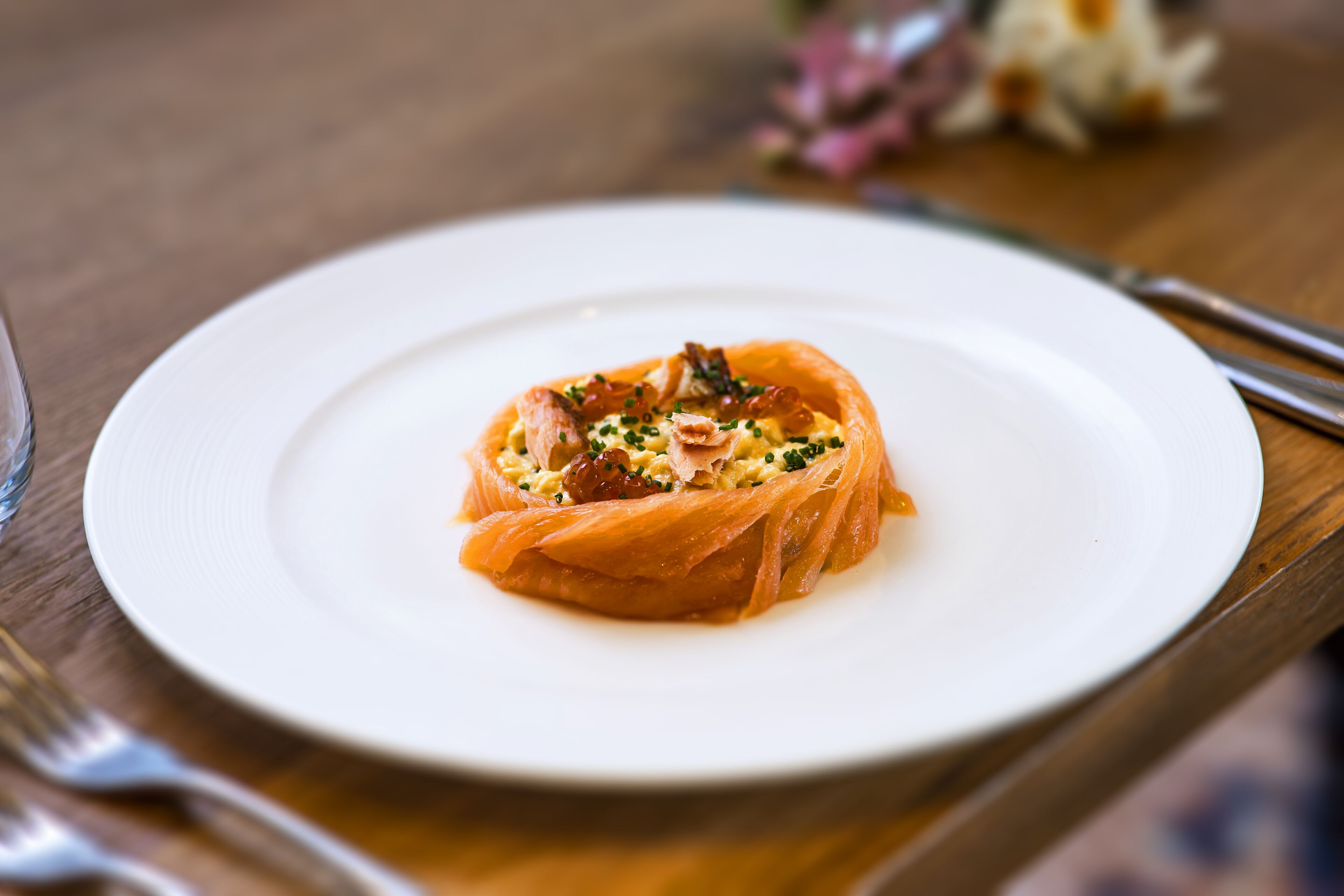A white plate with a dish of food on a wooden table.
