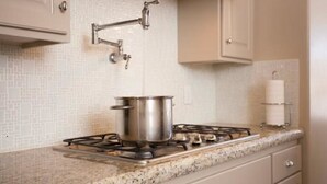 Una cocina con estufa a gas, una olla sobre la hornilla y un salpicadero de azulejos.