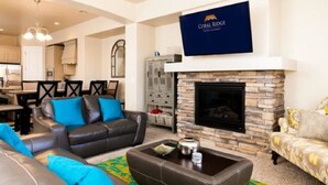 Una sala de estar con chimenea, sofás de cuero y un televisor de pantalla plana montado encima.