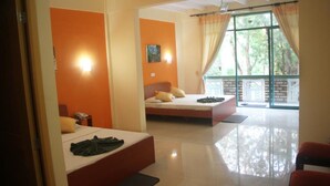 A hotel room with two beds, a large window with curtains, and a view of greenery outside. - Hotel Eden Garden (Inamaluwa)