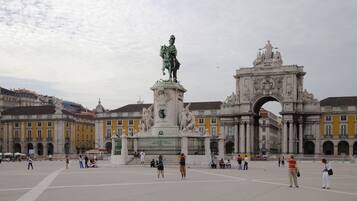 Una plaza pública con una estatua destacada y un arco decorativo.