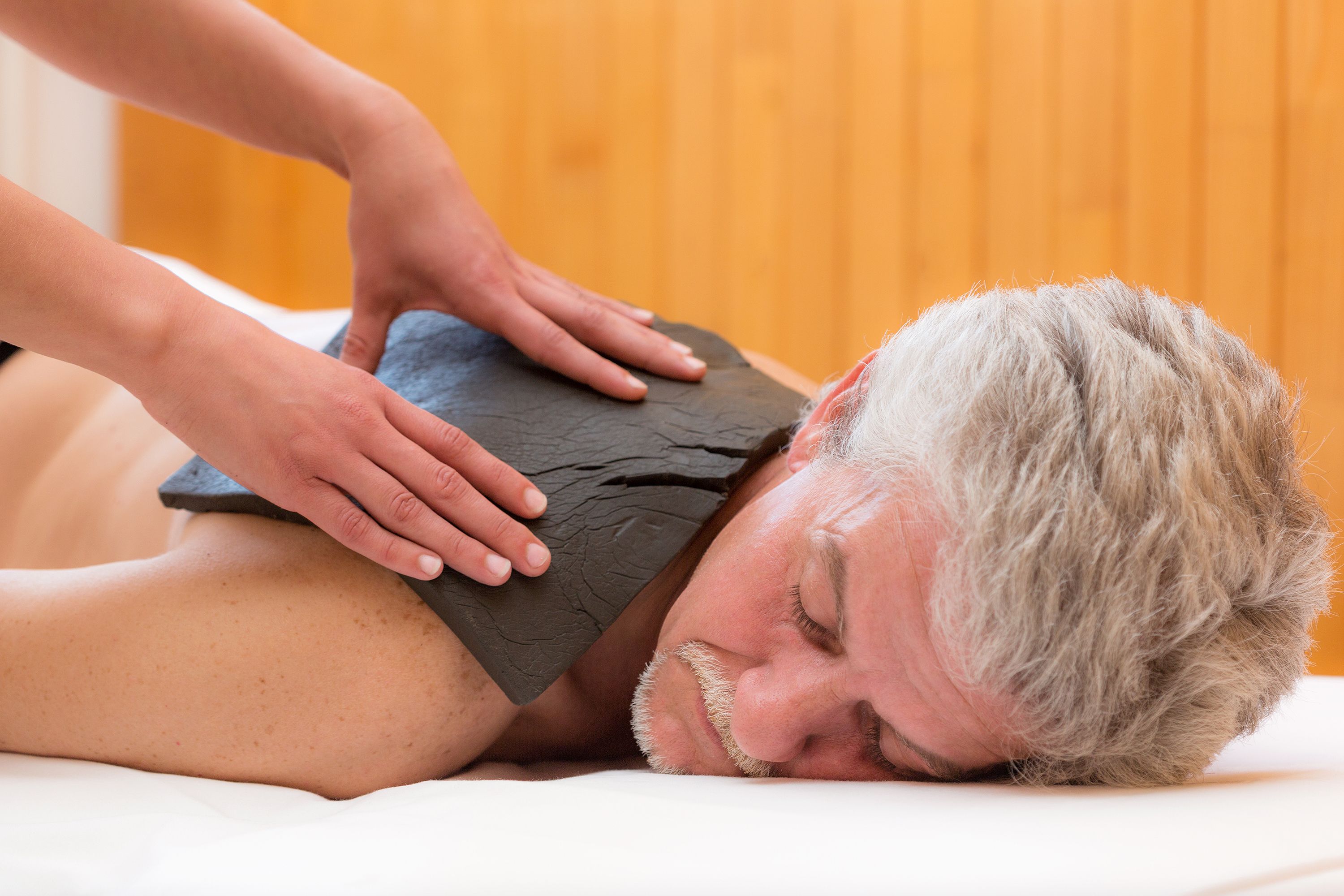 A person receiving a stone massage on their back.