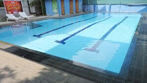 Una piscina con divisiones claras para carriles, un solado de azulejos y un cartelón al fondo.