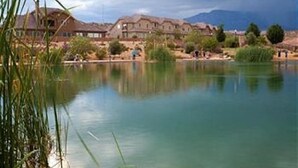 Vista con lago, un edificio grande, agua tranquila y vegetación circundante.