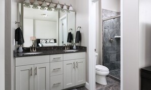 A modern bathroom with two sinks, a large mirror, and a shower area.