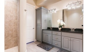 A bathroom with a double vanity, a large mirror, and a light fixture above the mirror.