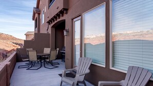 Un patio con mobiliario exterior, una parrilla y vistas a un paisaje montañoso.