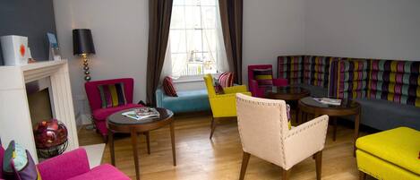 Un salon moderne avec une cheminée, un canapé, un fauteuil jaune et un canapé coloré à rayures.