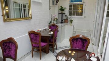 A dining area with a round table, purple upholstered chairs, and a mirror on the wall.