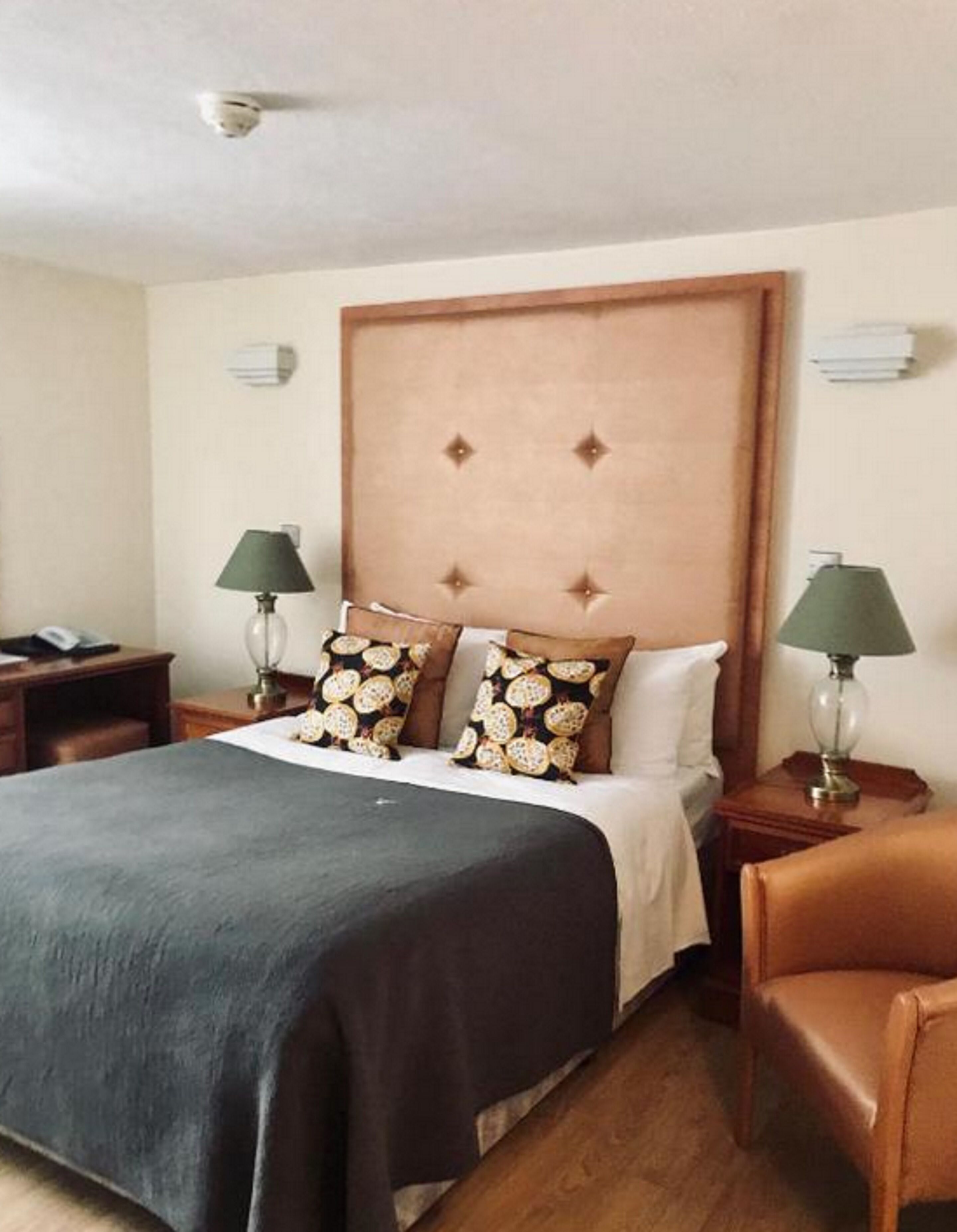 Une chambre d’hôtel avec un grand lit, deux tables de chevet, deux lampes et une chaise.