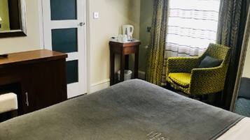 Une chambre d’hôtel équipée d’un lit, d’un bureau, d’une chaise, d’une télévision et d’une fenêtre avec des rideaux.
