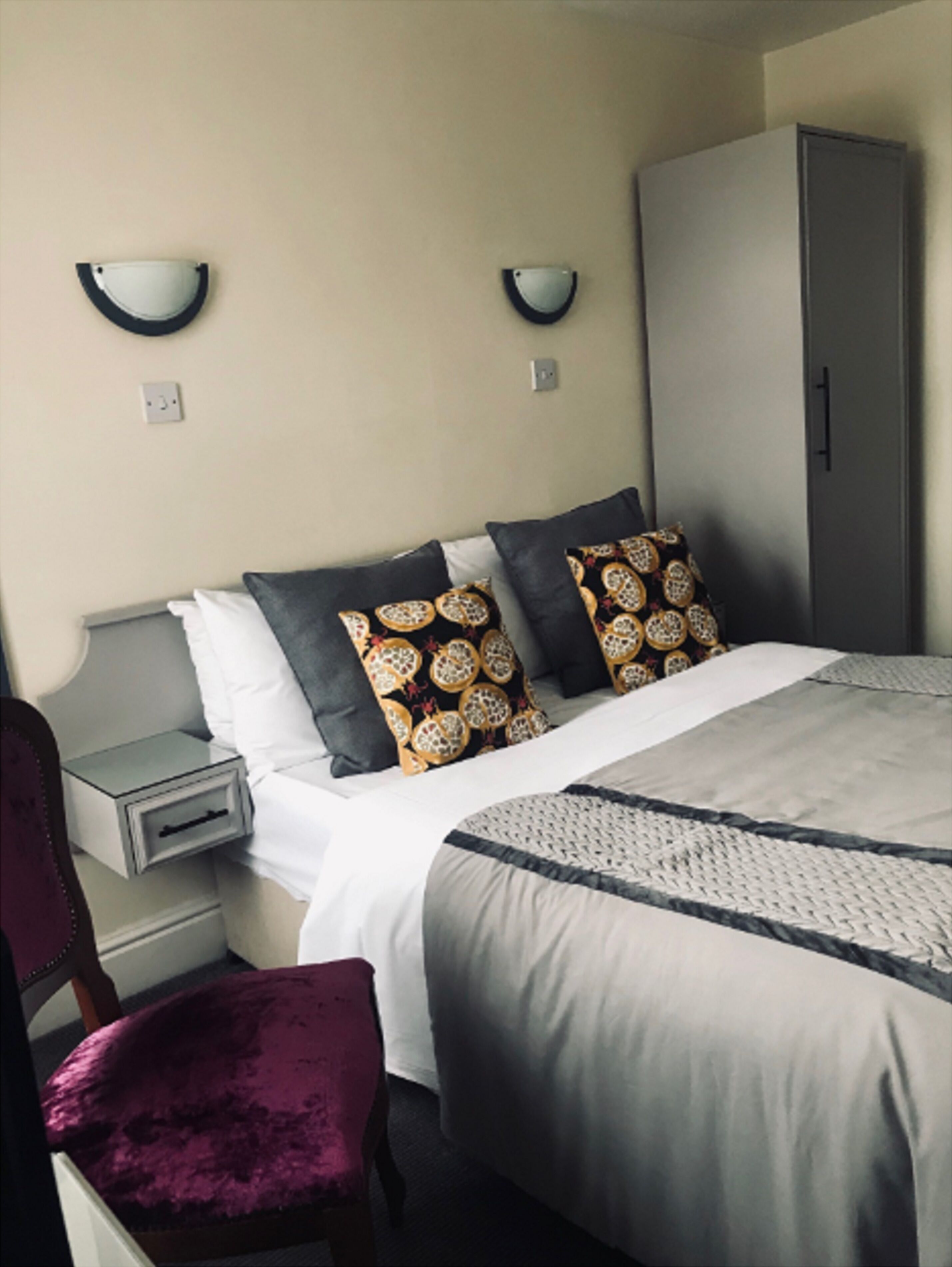A hotel room with a bed, a nightstand, a wardrobe, and a chair.