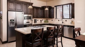 A kitchen with dark wood cabinets, stainless steel appliances, and a granite countertop. - Coral Vista Villa (Washington)