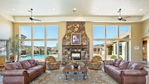 A spacious lobby with a stone fireplace, leather sofas, and large windows offering a view of a pool and landscape. - Coral Vista Villa (Washington)