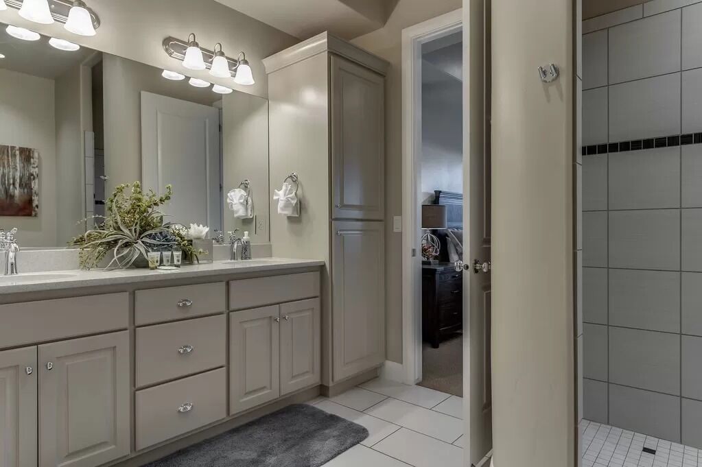 A modern bathroom with a large mirror, vanity, and a walk-in closet.