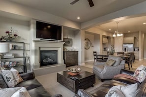 A modern living room with a fireplace, leather sofas, a coffee table, and a TV.