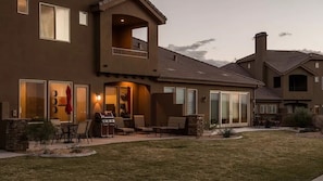 A two-story house with a patio area, outdoor seating, and a stone fireplace. - Golfer's Dream (Washington)