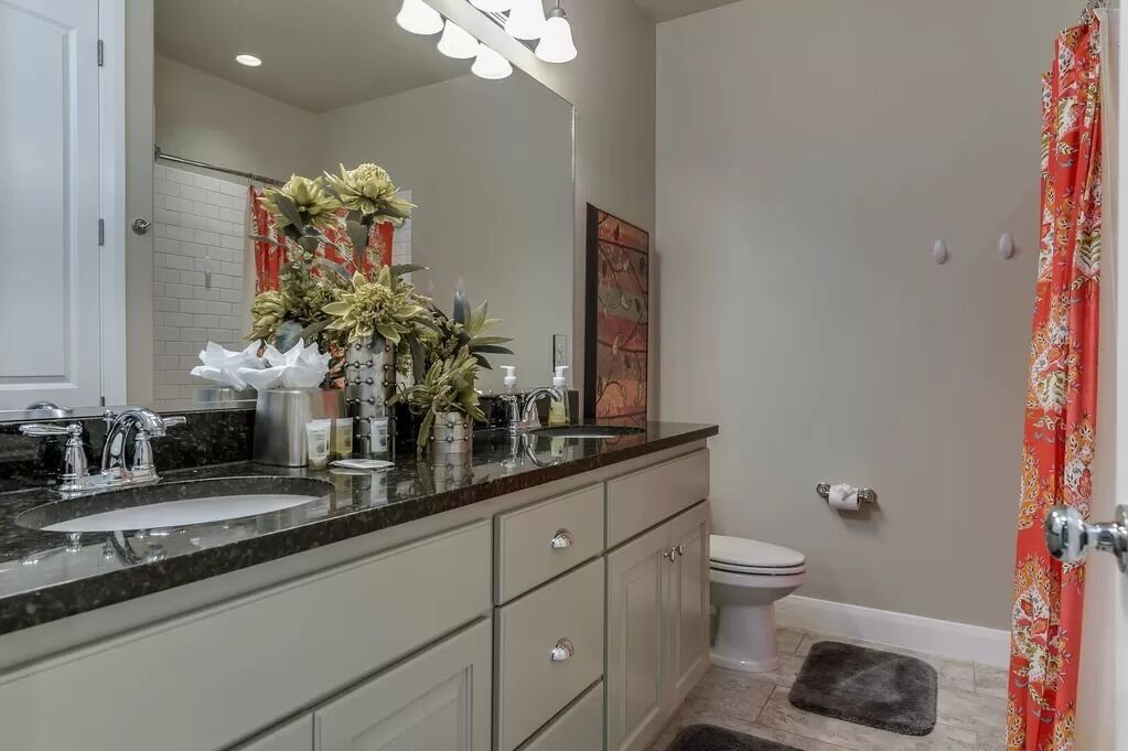 Un bagno moderno con uno specchio grande, due lavabi, un water e una zona doccia.