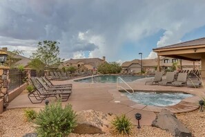 A pool area with lounge chairs and a hot tub, surrounded by stone walls and vegetation. - Golfer's Dream (Washington)