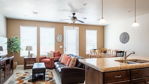 A modern living room with a sofa, coffee table, and a dining area with a kitchen island and sink. - Life is Good (Washington)
