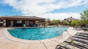 A swimming pool with lounge chairs and a covered area, surrounded by buildings and trees. - Life is Good (Washington)