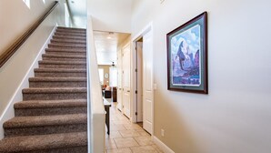 A staircase leading to a landing with a framed landscape painting on the wall. - Life is Good (Washington)