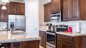A kitchen with dark wooden cabinets, stainless steel appliances, granite countertops, and a tiled backsplash. - Life is Good (Washington)
