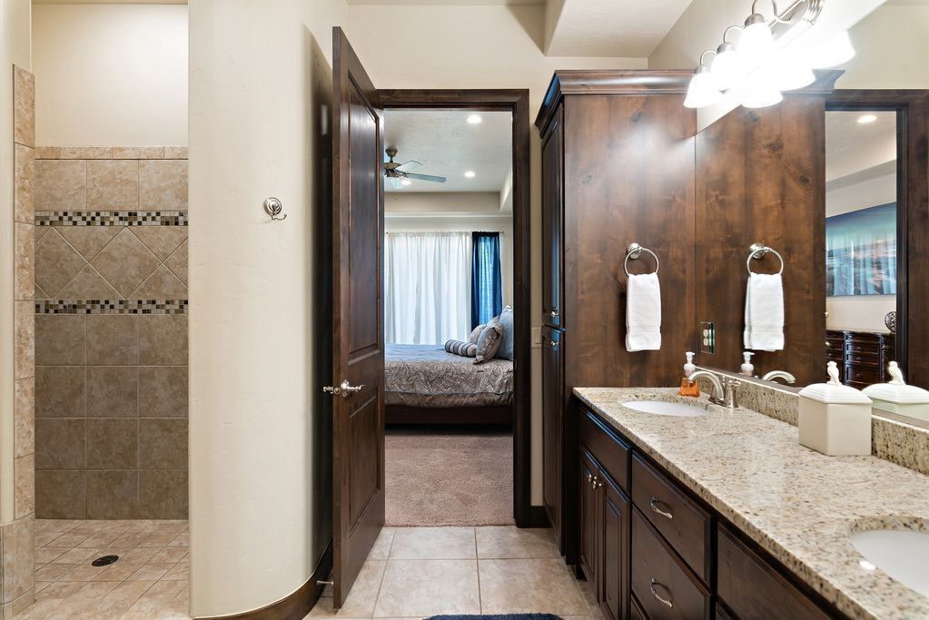 A modern bathroom with a walk-in shower, a large mirror, and a vanity with two sinks.