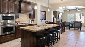 A modern kitchen with granite countertops, stainless steel appliances, and a central island with bar stools.