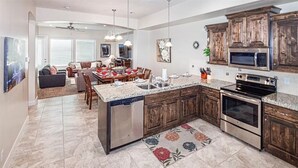 A spacious kitchen with granite countertops, wooden cabinets, a dishwasher, and a large island. - Pebble Beach (Washington)