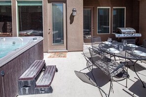 A patio with a hot tub, a grill, and a table set for dining. - Pebble Beach (Washington)