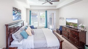 A bedroom with a large bed, a dresser, a television, and a ceiling fan. - Pebble Beach (Washington)