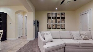 Una sala de estar con un sofá color beige, una mesita de centro y cuadros enmarcados en la pared.