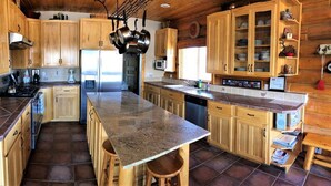 A kitchen with wooden cabinets, a granite countertop, and a central island. - Red Rock Ranch Cabin (Escalante)