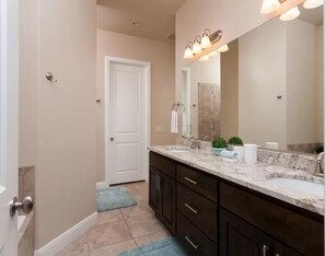 A modern bathroom with a large mirror, two sinks, dark cabinetry, and a marble countertop. - Red Cliffs (Washington)