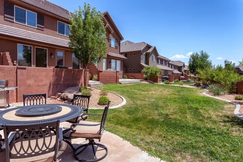 A residential area with houses, a patio with a table and chairs, and a well-maintained lawn.