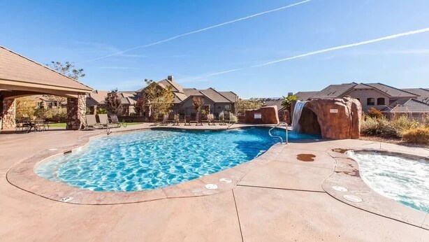A swimming pool with a waterfall feature, surrounded by stone buildings and a clear sky. - Solana Linda (Washington)
