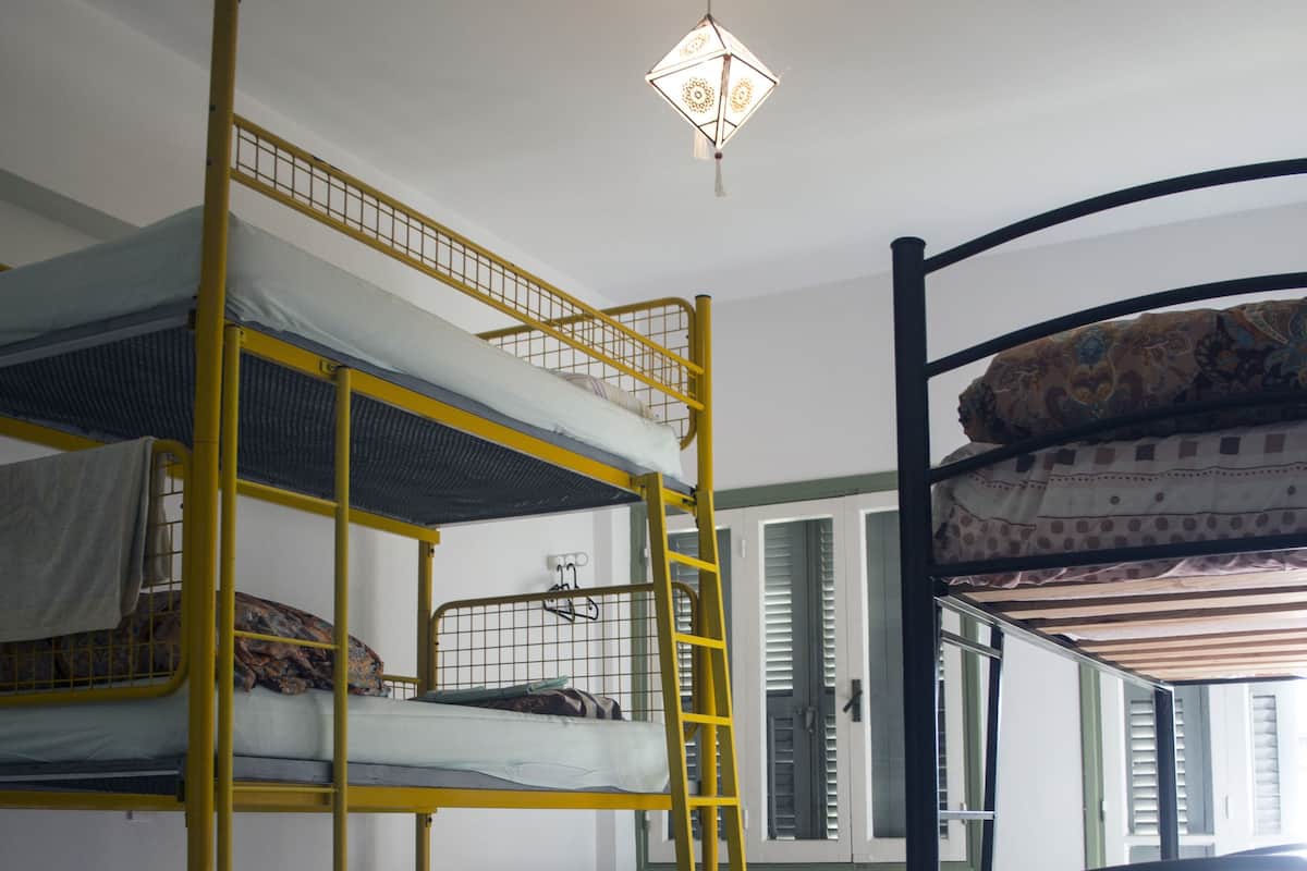 A dormitory room with bunk beds, a desk, and a chair.