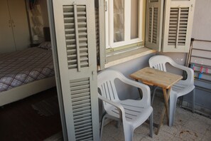 A compact room with a bed, a small table, two chairs, and a window with shutters. - Lima Sol House - Hostel (Limassol)