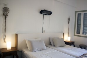 A bedroom with two beds, a wall-mounted heater, and a dreamcatcher. - Lima Sol House - Hostel (Limassol)