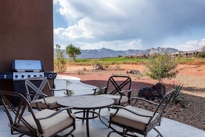 Une terrasse extérieure avec un barbecue, des sièges et une vue sur les montagnes.